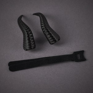 May include: Two black plastic horns with a textured surface and a black velcro strap.
