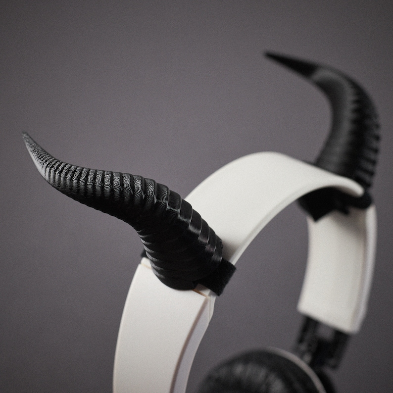 May include: White headphones with black horns attached to the headband. The horns are made of a textured plastic.