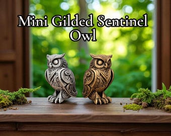 May include: Two Mini Gilded Sentinel Owl figurines. One is silver, the other is bronze. Both have detailed patterns and are perched on a wooden surface. The text "Mini Gilded Sentinel Owl" is above the owls.