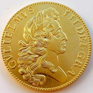 Könnte beinhalten: Eine goldene Münze mit dem Profil einer Person mit Lorbeerblättern und fließendem Haar. Die Münze hat einen geprägten Text am Rand. Die Münze hat eine detaillierte, strukturierte Oberfläche und einen geriffelten Rand.