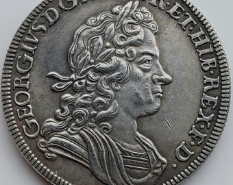 May include: A silver coin featuring a profile of a man with a laurel wreath and ornate text around the edge. The coin has a detailed design and a worn appearance, suggesting its age and historical significance.