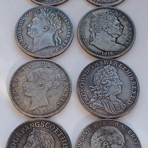 Peut inclure: Une collection de pièces de monnaie anciennes en argent, chacune représentant un profil de personnage historique. Les pièces présentent des inscriptions et des dates, dont "Victoria 1849" et "1816". Les pièces sont disposées en rangées, mettant en valeur leurs motifs.
