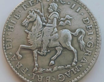May include: A silver coin featuring a detailed equestrian portrait of a figure holding a sword, with Latin inscriptions around the edge. The coin's design includes a horse and rider, with intricate details.