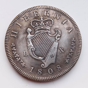 Peut inclure: Pièce de monnaie en argent avec l'inscription "HIBERNIA" et la date 1805. Elle présente une harpe, une figure couronnée et des détails complexes sur le bord. Une pièce historique.
