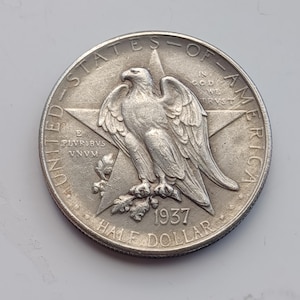Op de afbeelding: Een zilveren 1937 Half Dollar munt. De munt toont een adelaar op een ster, met de inscripties "UNITED STATES OF AMERICA" en "HALF DOLLAR". Het jaartal 1937 is zichtbaar.