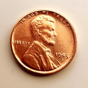 Op de afbeelding: Een koperkleurige Lincoln-munt uit 1943. De voorzijde toont een profiel van Abraham Lincoln, het woord "LIBERTY" en de zin "IN GOD WE TRUST". Het jaartal "1943" en het muntteken "S" zijn ook zichtbaar.