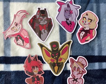 Puede incluir: Conjunto de 8 pegatinas de personajes de dibujos animados con personajes de la serie animada "Hazbin Hotel". Las pegatinas están impresas en vinilo blanco y presentan una variedad de personajes, incluidos Angel Dust, Alastor, Charlie, Vaggie, y más.