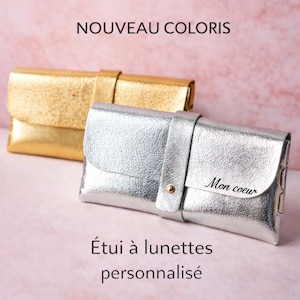 Può includere: Due custodie per occhiali in pelle, una dorata e una argentata, sono esposte su uno sfondo rosa. La custodia argentata riporta la scritta "Mon coeur". Sono visibili anche i testi "NOUVEAU COLORIS" e "Étui à lunettes personnalisé".
