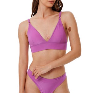 Könnte beinhalten: Ein zweiteiliges Dessous-Set in einem leuchtenden Lila. Das Oberteil ist ein Triangel-BH mit verstellbaren Trägern. Die passenden Unterteile sind ein klassischer Bikini-Schnitt. Das Set ist aus einem glatten, einfarbigen Stoff gefertigt.