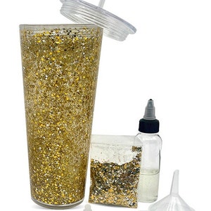 May include: A clear plastic tumbler with a gold glitter design, a clear plastic lid, a straw, a small bag of gold glitter, a clear plastic bottle with a black cap, and a clear plastic funnel.