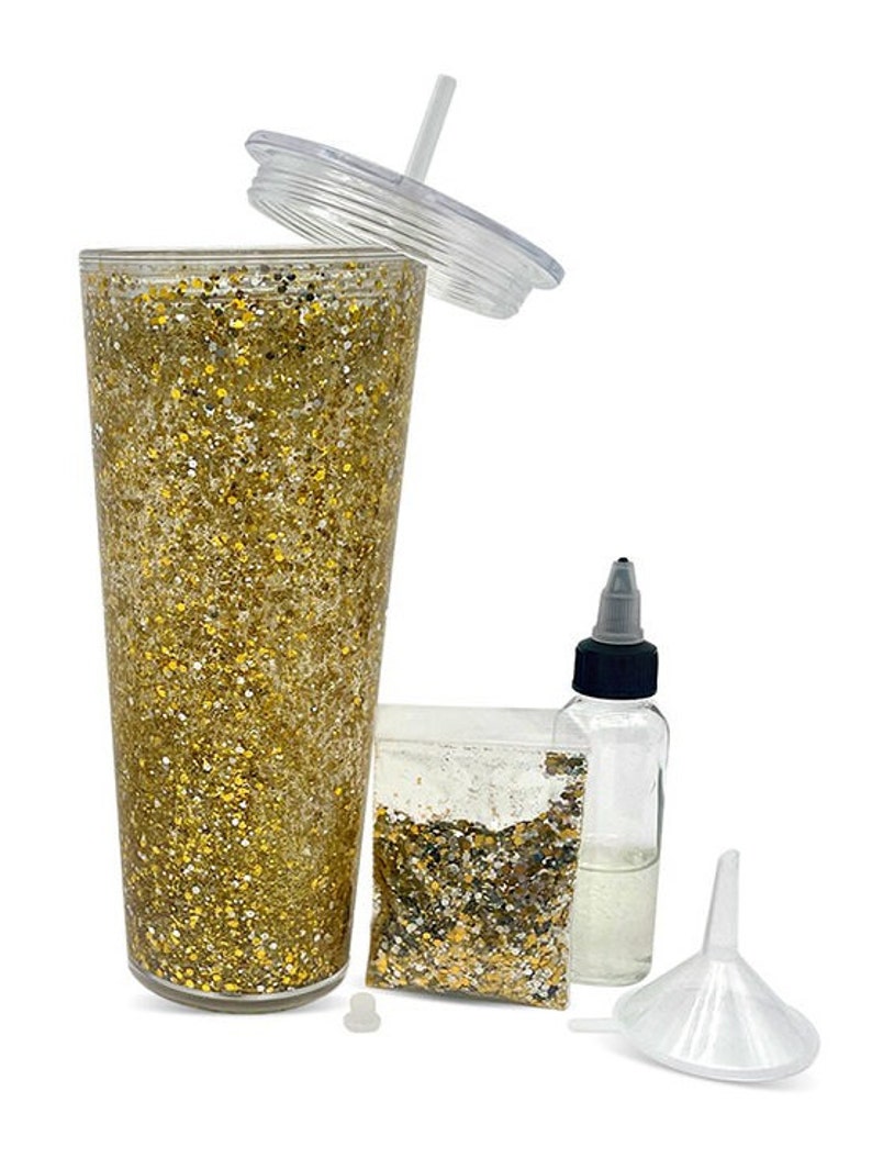 May include: A clear plastic tumbler with a gold glitter design, a clear plastic lid, a straw, a small bag of gold glitter, a clear plastic bottle with a black cap, and a clear plastic funnel.