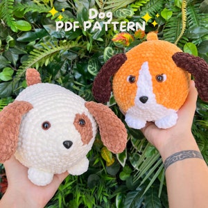 May include: Two crocheted dog plushies, one white with brown ears and one orange with brown ears. The plushies have black eyes and a black nose. The text "Dog PDF Pattern" is written above the plushies.