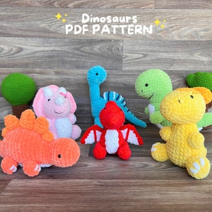 May include: A set of six crocheted dinosaur toys, including a green, a blue, a pink, a red, a yellow, and an orange dinosaur. The dinosaurs are all sitting on a wooden surface. The text "Dinosaurs PDF PATTERN" is written above the dinosaurs.