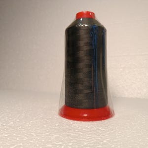May include: A spool of black thread wrapped in clear plastic with a red plastic cap.