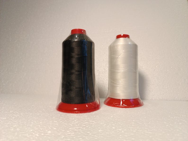 May include: Two spools of thread, one black and one white, with red plastic caps. The spools are wrapped in clear plastic.