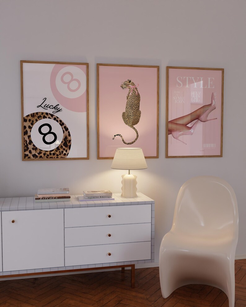 May include: Three framed prints with a pink background. The left print features a black and brown leopard print with a white number eight and the text "Lucky 8". The middle print features a pink leopard sitting on a pink background. The right print features a pair of legs with pink high heels and the text "Style".