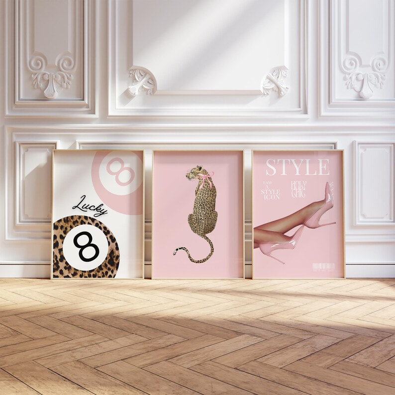 May include: Three pink framed prints with different designs. The left print features a black and brown leopard print with the number 8 and the word "Lucky" in black text. The middle print features a pink background with a black and brown leopard sitting on its hind legs. The right print features a pink background with a pair of pink high heels and the word "STYLE" in white text.