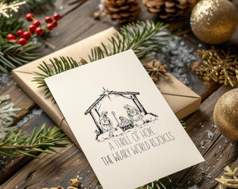 May include: A white Christmas card with a black and white illustration of the nativity scene. The card reads "A thrill of hope, the weary world rejoices."