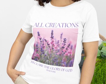 May include: White t-shirt featuring a floral design with lavender and pink flowers. The text "ALL CREATIONS" is above the image, and "DECLARE THE GLORY OF GOD" and "PSALM 19:1" are below. The shirt has short sleeves.