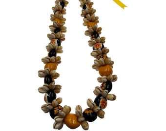Puede incluir: Un collar de conchas amarillo y negro con flores naranjas. El collar está hecho de pequeñas conchas redondas que están enhebradas en una cinta amarilla.