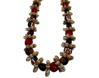 May include: A traditional Hawaiian lei made of white, black, and red shell beads. The beads are strung together with a red ribbon.