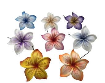 Puede incluir: Un surtido de nueve flores artificiales de plumeria en varios colores, incluyendo azul, morado, rosa, amarillo y naranja. Cada flor tiene múltiples pétalos y un centro oscuro, perfecto para accesorios para el cabello o proyectos de manualidades.