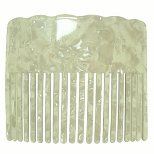 Puede incluir: Un peine blanco con un patrón de mármol. El peine tiene una parte superior curva y una fila de dientes.