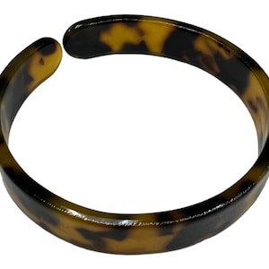 Peut inclure: Un bracelet jonc en écaille de tortue brun et noir.