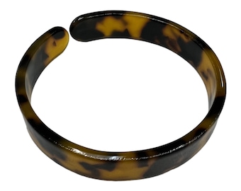 Puede incluir: Un brazalete de brazalete de carey marrón y negro.