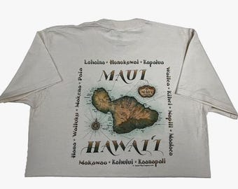 Puede incluir: Camiseta color crema con un mapa de Maui, Hawái, con la palabra "MAUI" encima del mapa y "HAWAII" debajo. La camiseta también incluye nombres de lugares alrededor del mapa y una rosa de los vientos.