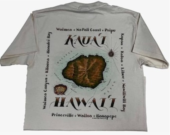 Puede incluir: Una camiseta blanca con un mapa de Kauai, Hawái, con nombres de lugares circundantes. La palabra "KAUAI" está arqueada sobre la isla, y "HAWAII" está arqueada debajo. Una rosa de los vientos está en el centro.