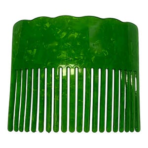 Puede incluir: Un peine de plástico verde con un borde superior ondulado y dientes espaciados uniformemente. El peine tiene un aspecto veteado y está diseñado para el cuidado del cabello. El peine es de un tono verde vibrante.