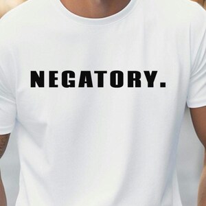 May include: White t-shirt featuring the word "NEGATORY." in bold, black capital letters. The shirt has a crew neck and short sleeves, a classic casual style.