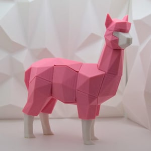 May include: A pink geometric alpaca figurine with white legs and face. The alpaca is made of interlocking pieces and has a modern, abstract design.