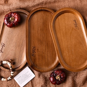 May include: Three oval wooden trays with engraved names "Riley", "Madi", and "Bryce". The trays are made of light brown wood and have a smooth, polished finish.