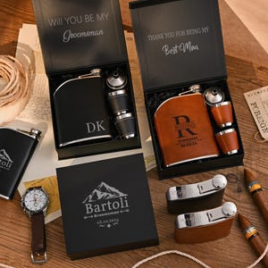 Puede incluir: Dos petacas de metal forradas en cuero negro y marrón en cajas de regalo con vasos de chupito a juego. Una tapa dice Will You Be My Groomsman, la otra Thank You For Being My Best Man. Incluye un reloj de pulsera, dos petacas y dos puros.