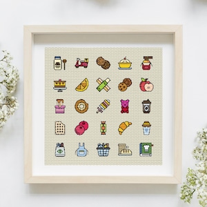 Puede incluir: Un bordado de punto de cruz enmarcado con iconos de comida coloridos. Los iconos incluyen galletas, una rebanada de pastel, una rosquilla, un cruasán y una taza de café. El fondo es de tela beige claro y el marco es de madera clara.
