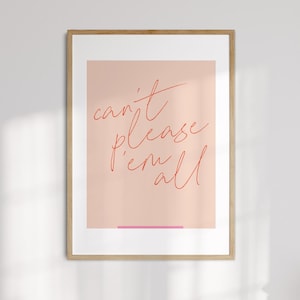 Könnte beinhalten: Gerahmter Kunstdruck mit dem Schriftzug "can't please 'em all" in roter Schrift auf hellrosa Hintergrund. Am unteren Rand befindet sich eine dünne rosa Linie. Der Rahmen hat eine helle Holzfarbe.