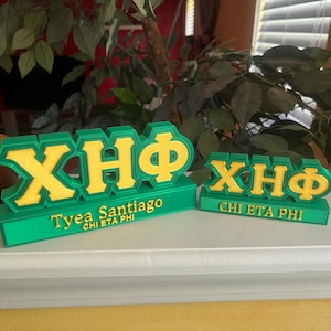 Può includere: Due targhe con lettere greche verdi e dorate. La targa più grande recita "ΧΗΦ Tyea Santiago CHI ETA PHI". La targa più piccola recita "ΧΗΦ CHI ETA PHI".