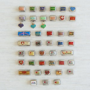 May include: A collection of silver-toned charm bracelets with various inscriptions and heart-shaped accents. The charms include phrases like "Mom," "Sister," "Daughter," and "Grandpa." Some charms have colorful enamel details.