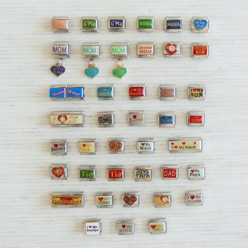 May include: A collection of silver-toned charm bracelets with various inscriptions and heart-shaped accents. The charms include phrases like "Mom," "Sister," "Daughter," and "Grandpa." Some charms have colorful enamel details.