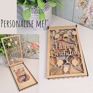 May include: A wooden card holder with a slot for cash. The card holder is decorated with a cut-out design of balloons and the words "Happy Birthday".