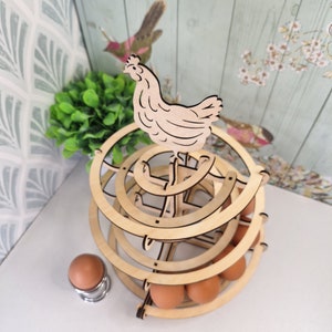 May include: Wooden egg holder shaped like a chicken with a tiered design. The holder is made of natural wood and has a rustic look. It can hold up to 12 eggs.