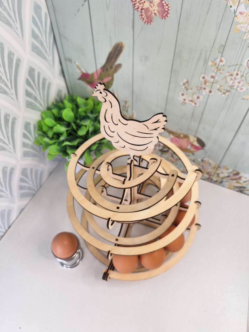May include: Wooden egg holder shaped like a chicken with a tiered design. The holder is made of natural wood and has a rustic look. It can hold up to 12 eggs.