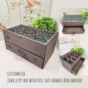 May include: A grey wooden jewellery box with two pull-out drawers and a decorative, openwork lid. The lid and drawer fronts feature floral designs. The interior is lined with teal fabric. The text on the image reads "CUSTOMISED JEWELLERY BOX WITH PULL OUT DRAWER AND MIRROR."