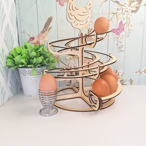 May include: Wooden egg holder shaped like a chicken with a spiral design. The holder is filled with brown eggs.