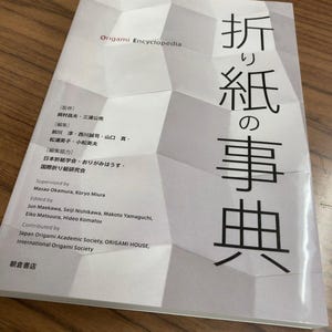 Könnte beinhalten: Ein weißes Buch mit dem Titel "Origami Encyclopedia" und dem japanischen Text "折り紙の事典" in Schwarz. Das Buch handelt von der Kunst des Origami.