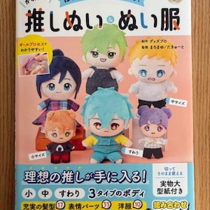 以下が含まれることがあります： 「推しぬいぬい服」というタイトルの日本語の本の表紙。表紙には、さまざまな表情と服装をしたカラフルなぬいぐるみキャラクターのイラストが描かれている。この本には、ぬいぐるみと服を作るための説明書が掲載されている。
