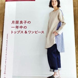 May include: A book cover with a woman wearing a light brown and blue striped dress and blue jeans. The book title is "月居良子の 一年中の トップス&ワンピース" which translates to "Tops & Dresses for the Year by Ryo  Tsukii".