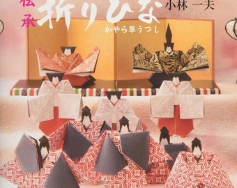 May include: A book titled "Folding Hina Dolls:  A Step-by-Step Guide" with a colorful illustration of origami dolls on the cover. The book is written in Japanese and features the text "Folding Hina Dolls" in English.